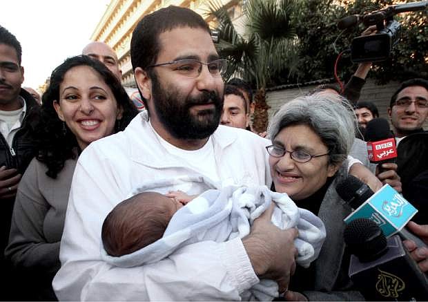FILE - In this Sunday, Dec. 25, 2011 file photo, Egyptian prominent blogger Alaa Abdel-Fattah, center, holds his newborn son, Khaled, as he stands with his mother Laila Soueif, right, and his sister Ahdaf Soueif, left, after his release, in Cairo, Egypt. Egyptian security forces arrested the prominent political activist Thursday night, Nov. 28, 2013 over inciting a demonstration in defiance of a new law heavily restricting protests in the country, his family said. The arrest of Abdel-Fattah, a blogger who rose to prominence in Egypt&#039;s 2011 revolution, quickly dominated social media. His previous detention sparked protests against the military, which appeared likely again as recently quiet liberal and secular groups have expressed increasing alarm over the military-backed government since it enacted the new protest law this week. (AP Photo/ Amr Hafez, File)