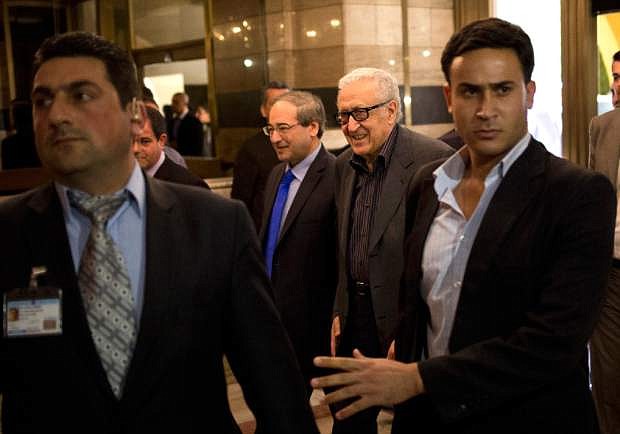 U.N.-Arab League envoy Lakhdar Brahimi, center right, and Deputy Syrian Foreign Minister Faisal Mekdad arrive to a hotel surrounded by security Monday, Oct. 28, 2013 in Damascus, Syria. Brahimi is on his first trip to the country in almost a year. (AP Photo/Dusan Vranic)
