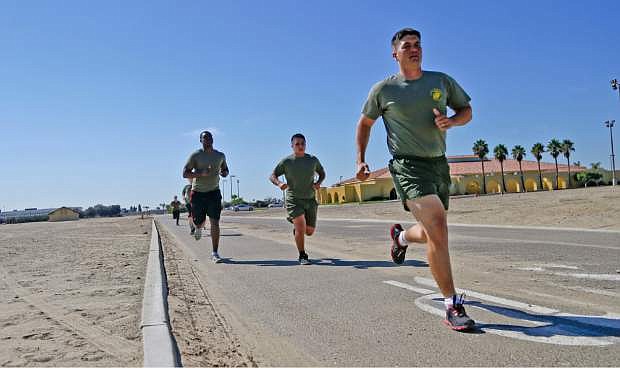 In a Thursday, Oct. 17, 2013 photo, an instructor pulls away from a group of service members on a three mile run at the Marine Corps Recruit Depot in San Diego.  The group members have failed the so-called &quot;tape test&quot; and are trying to improve their conditioning to avoid being kick out of the military. Doctors say a number of military personnel are turning to liposuction to remove excess fat from around the waist so they can pass the Pentagon&#039;s body fat test. Some service members say they have no other choice because the Defense Department&#039;s method of estimating body fat is weeding out not just flabby physiques but bulkier, muscular builds. A number of fitness experts and doctors agree, and they&#039;re calling for the military&#039;s fitness standards to be revamped.  (AP Photo/Lenny Ignelzi)