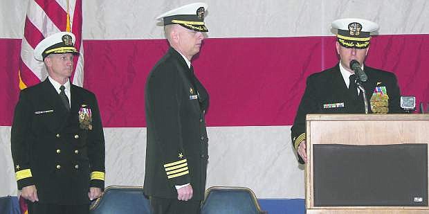 Capt. David Halloran, right, reads his orders on Friday  to become the new commanding officer of Naval Air Station Fallon as Rear Adm. Mark Rich, left, and Capt. Leif Steinbaugh, the outgoing commander, look on.