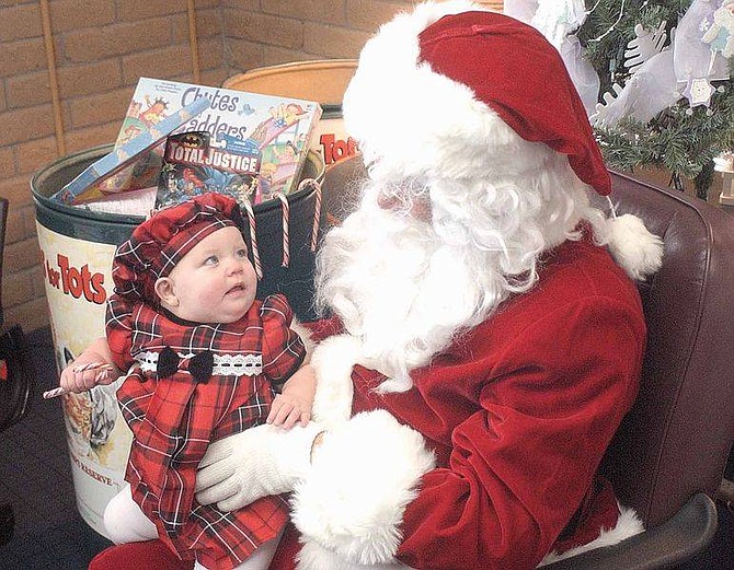 Brian CorleyZoe Stewart, 8 months, looks up at Wendell Ferris who is dressed up as Santa Claus at a collection site for the Toys for Tots program. Children brought toys which will be given to families that need them for a chance to sit on Santa&#039;s lap and have their picture taken.