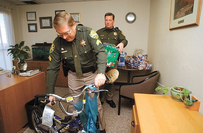 Carson City Sheriff&#039;s Seargent Ronald John, with bike, and deputy Scott Davis pick up presents from the Ron Wood Family Resource Center Friday morning. The Carson City Sheriff&#039;s Dept adopted a deserving and delivered the presents to their home.  photo by Rick
