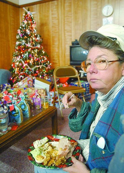 Lin Lennon sits in the Jubilee Center in front of a Christmas tree eating her free Christmas dinner. The center, which helps those in need, gave out a free dinner to its members who have sought help. Photo by Brian Corley