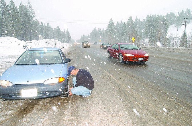 Brian Corley photoGustavo Villegas puts chains on his car at Spooner Summit after road conditions worsened on Friday afternoon.