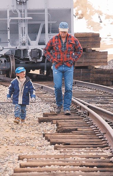 Four-year-old Daniel Fegert walks with Gold Hill Railroad Volunteer Richard Feutz near the Gold Hill Depot Friday afternoon. Richard Feutz and Kim Fegert (not shown) are having a fundraiser to restore and Depot and add a section of track.  photo by Rick Gunn