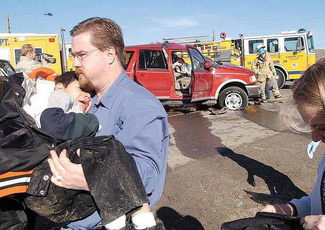 Rick Gunn photoA bystander carries one of two children involved in a traffic collision on Thursday. The children were unhurt, but their mother was injured.
