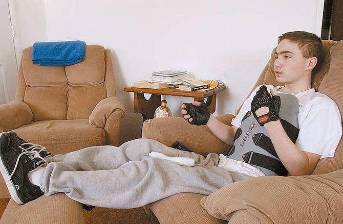 Kevin Petersen, 14, watches tv in his home in Carson City Thursday afternoon.  Petersen was the victim of a rollover traffic accident and just recently got out of the hospital.  photo by Rick Gunn