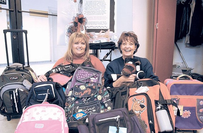 Lori Hadlock, executive director of Platinum + salon, and Susie Bendure, salon advance stylist, sit with backpacks the salon is collecting for foster children. The salon is hosting a community service project to give Northern Nevada children removed from their homes a backpack and personal hygenie items. Photo by Rick Gunn