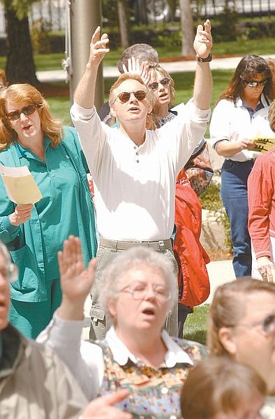 David Shipman and Joann Jacot, foreground, raise their arms in prayer at the Capitol steps during a noon National Day of Prayer Thursday. Close to 100 people came to the steps to sing and pray as other prayer circles gathered throughout Carson City including at the flag pole at Carson High School. Photo by Brian Corley