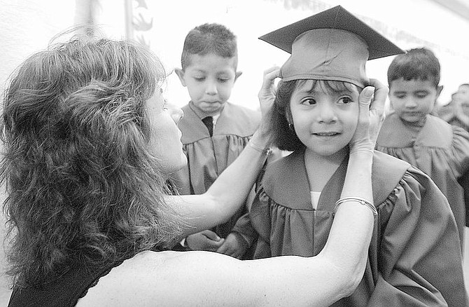 Even Start Pre-kindergarten graduate Keibi Mejia, 5 smiles while getting her cap during the 2001-02 graduation at Empire Elementary school Wednesday evening.  Placing the cap is Even Start&#039;s Peggy Sweetland.  photo by Rick Gunn
