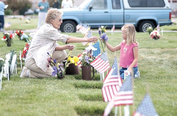 Barbara Atkins, left, and her grandduaghter, Rachel Smith, 6, plant flowers picked from Atkins&#039; garden at the grave of Atkin&#039;s husband who served during WWII and the Korean Conflict before dying four years ago. Photo by Birna Corley