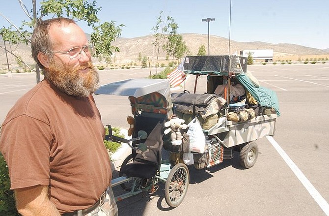 Kieth Beard stands next to his tricycle and traylor which he has pulled since leaving the Fresno area. Beard has no final destination planned but keeps riding with his dog, Honey.