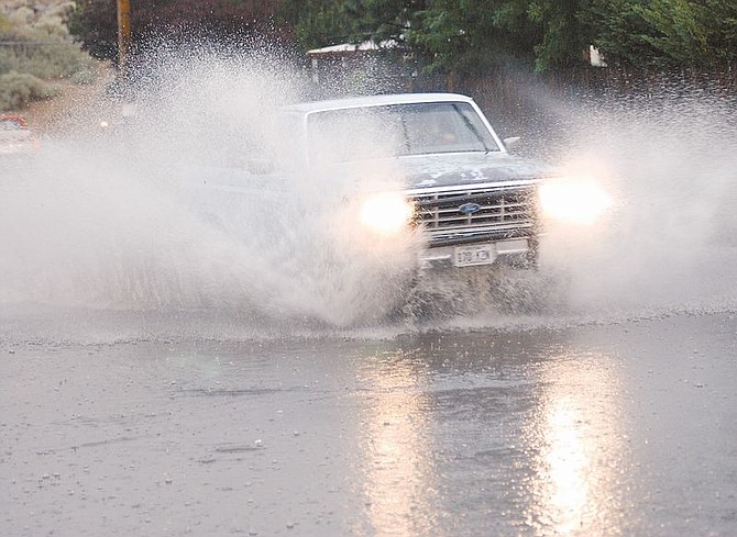 A pick-up truck drives west along a flooded portion of East Winnie during a brief downpour Saturday afternoon. Photo by Brian Corley