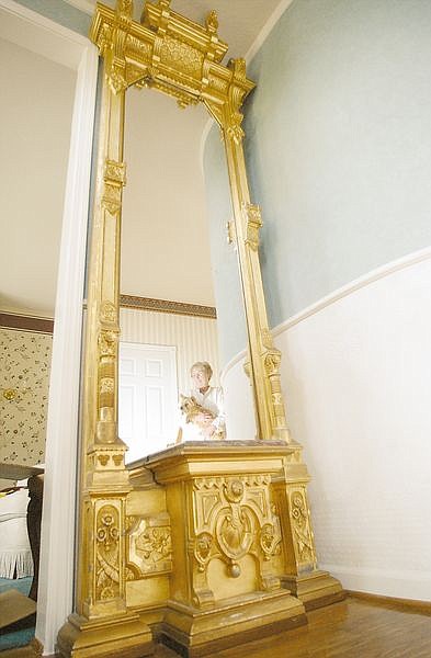 Shirlee Veverka stands next to a vintage mirror which was originally a part of the Rinckel Mansion Wednesday afternoon.  She has positioned it in her new home.