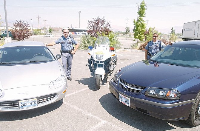Nevada Highway Patrol troopers Matt Zacha, left, and Cindy Campbell stand next to two new NHP patrol cars, a Chrystler Concords and a Chevrolet Impala which will be unmarked. Troopers in the cars will look specifically for aggresive drivers who put others at risk. Photo by Brian Corley