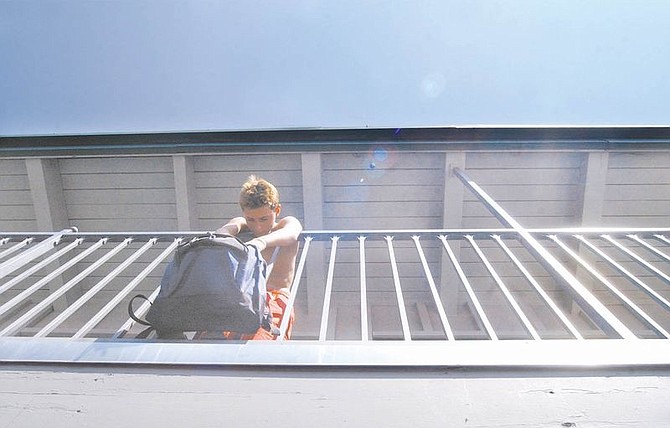A 12-year-old boy hangs over the balcony of the Downtowner Motel on Wednesday. Homeless advocate Kim Riggs and Costco volunteers delivered backpacks filled with school supplies to children living in motels and shelters.