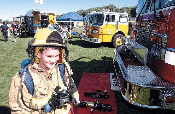 Photo by Brian CorleyAlex Parker, 11, tries to walk around a fire engine with fire gear Sunday at the Sept. 11th memorial at Mills Park. Hundreds of people came out to remember those that died and to look at Fire, police and military equipment on display.