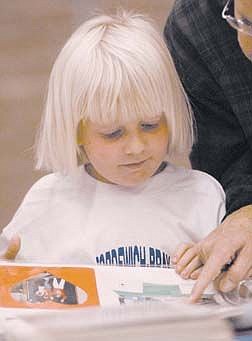 Debbrah, 6, looks at an old scrapbook with Donna Schellin from Bordewich-Bray Elementry School. Photo by Brian Corley