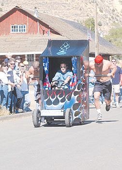 Shawn Lass, Left, and Scott Burgess, right, push the Butt Hut II as Tami ward stears the modified outhouse up E Street during the outhouse races in Virginia City Saturday. Photo by Brian Corley