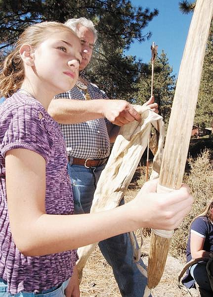 Rick Gunn photoEleven-year-old Samantha Rhine looks over a replica of a Native American bow while John Roos of the University of Nevada, Reno, cooperative extensive office displays a quiver and arrow Tuesday at Clear Creek Camp.