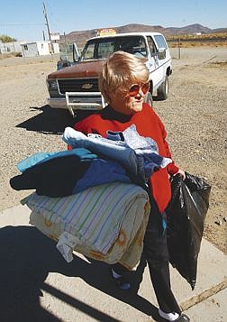 Betty McCurry carries the first donation of clothes and hangers to front of the new Lyon County FISH store. McCurry who lives just a few blocks from the store plans on volunteering time. Photo by Bran Corley