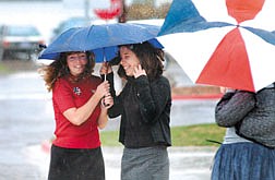 Left to right Michelle Mauer, 14 and Caitlyn Carr, 13, try to stay dry in front of Carson Middle School Friday morning. A strong Pacific Storm is expected to bring precipitation through the weekend.