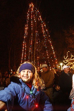 Emilie Barnes, 5, sits in front of the Christmas Tree that was lit Thursday evening at the Capital steps. Nearly 1,000 people came to the event to listen to christmas carols and see Santa Claus. Photo by Brian Corley