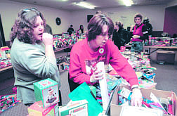 Salvation Army volunteer Cathie Timmons digs through a box of donated toys to show Carrie Harrah. Harrah spent Tuesday in a last-minute spree sponsored through the Salvation Army. Photo by Rick Gunn.