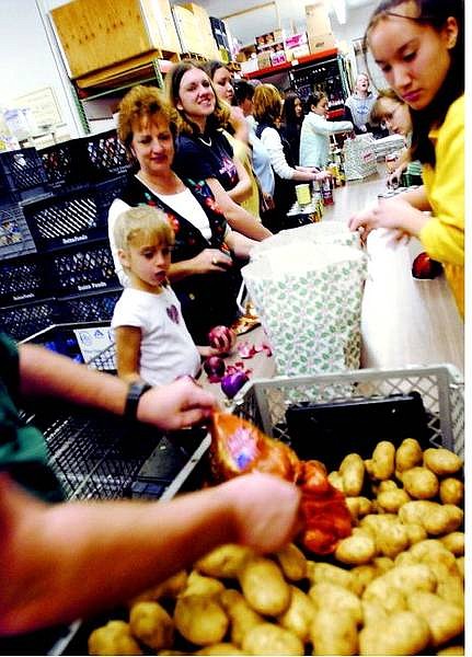 BRAD HORN/Nevada Appeal David Eiswert dumps potatos into a shopping cart as he daughter Emily, 7, watches at FISH Saturday morning.