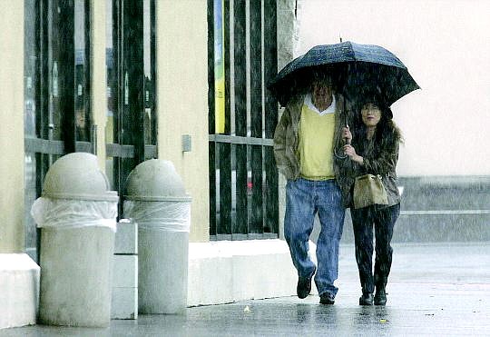 CATHLEEN ALLISON/NEVADA APPEAL An unidentified couple walk throught the rain on Monday afternoon in front of Smiths in Carson City.  A chance of rain and snow will continue in the area through the New Year.