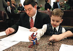 Nevada Assemblyman Bob McCleary, D-North Las Vegas,  prepares for opening day ceremonies at the Legislature, in Carson City, Nev., on Monday, Feb. 3, 2003, as his son Jacob, 4, plays with Spiderman.  Lawmakers convened in Carson City for the 2003 legislative session. (AP Photo/Nevada Appeal, Cathleen Allison)