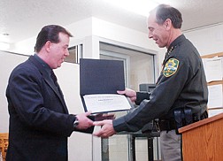 John Henderson, left, recieves a certificate from Carson City Sheriff Kenny Furlong for his actions to help restrain a man armed with several weapons who entered K-Mart Jan. 16. Henderson, an employee of K-Mart and two other employees, Bob Cary and Robin Cooper, restrained the man until the Carson Sheriff&#039;s department was able to take the man into custody. Photo by Brian Corley