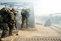 U.S. Army soldiers from A Company 3rd Battalion 7th Infantry Regiment approach an injured woman who was caught in the crossfire with Iraqi forces over the Euphrates River when the U.S. Army siezed a bridge in Al Hindiyah, Iraq Monday, March 31, 2003. The Army&#039;s Task Force 4-64, part of the 3rd Infantry Division, took the strategic bridge in it&#039;s move north towards Baghdad. The woman, who was near a dead  civilian man, was bleeding and apparently shot in the buttock. (AP Photo/John Moore)