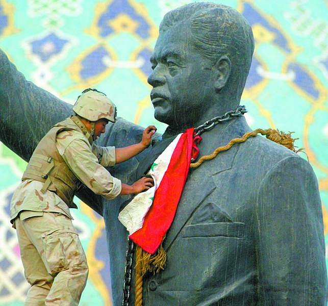 Associated PressCpl. Edward Chin of New York, 3rd Battalion, 4th Marines Regiment, sets up an Iraqi flag around the neck of a statue of Iraqi President Saddam Hussein before it was torn down in Bagdad, Wednesday.