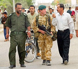 British Royal Marines&#039; captain Simon Rogers from Kent, center, talks to a resident in Al Faw, south of Basra, southern Iraq, as he helps Iraqi policeman Moyet Abdul Jabar, left, to patrol the streets, Sunday, April 13, 2003. British troops and Iraqi policemen worked together as a first stage in efforts to restore order following mass looting in recent days after the Iraqi regime was ousted. (AP Photo/Terry Richards/Pool)