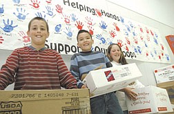 Alex Levine, 9, Kenny Mullis, 9, and Jessie Holmes, 10, hold up boxes of supplies their school collected to send to troops in Iraq. Students at Sutro Elementary School in Dayton collected 727 pounds of goods to send. Photo by Rick Gunn.