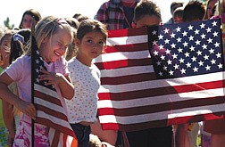 Kindergartener Shania Hicks,6, giggles during  a flag ceremony at Fremont School Tuesday morning. Standing next to her i  Elizabeth Bracamontes, 6,  and Brandon Iza, 7,  behind flag.
