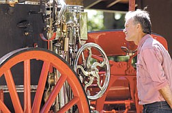 Former Virginia City volunteer firefighter Tom Gray eyes the lubricating system on the antique steam pump Wednesday afternoon in Pleasant Valley.   The steamer will be in Virginia City&#039;s Fourth of July parade.  photo by Rick Gunn