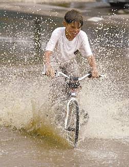 Photo by belinda grantScotty White 13yrs of Indian Hills joy rides his bike through large bodies of water in Indian hills on Vista Grande Blvd. Two fires were caused by lightning and both were put out by rain. The fire fighters said it was raining cats and dogs.