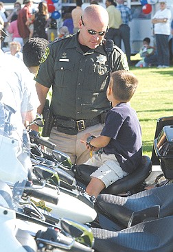 William Cullen, 6 looks at his father Carson City Sherrif Seargant Mike Cullen while sitting on one of the patrol bikes Tuesday afternoon at the National Night Out celebration Tuesday evening. photo by Rick gunn