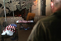 An American soldier in Tikrit, Iraq, Friday, Sept. 19, stands guard over the flag draped bodies of  unidentifed  soldiers who died late Thursday evening, Sept. 18, 2003, after their squad was ambushed while on patrol.  The coordinated attack against U.S. forces cost the lives of three soldiers and wounded another two. &#124; Rob Griffith
