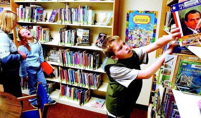 BRAD HORN/Nevada Appeal Cameron Childers, 10, of Carson, searches for a book while his sister Kayse, 10, talks to her mother at the Carson City Library Friday.
