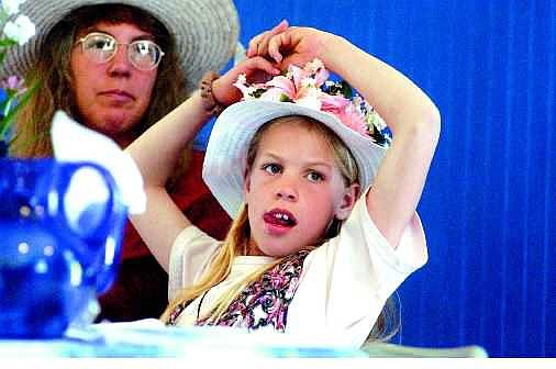 BRAD HORN/Nevada Appeal Deborah Drinkle, 10, of Cold Springs, watches the infamous Abbott and Costello skit &#039;Who&#039;s on First,&#039; during the Mad Hatter tea party at the Boys &amp; Girls Club gym in Carson City on Saturday. At top, 8-year-old Zena Wilson, back right, tries on Kim Lindley&#039;s hat at the tea party. Sitting next to Zena, going clockwise are Lindley, Christi Hester, Barbara Mikuta and Jaime Cole.