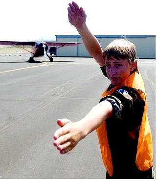 BRAD HORN/Nevada Appeal Donald Manly, 15, of the Civil Air Patrol, guides a plane at the Carson Airport on Saturday during the first experimental aircraft fly-in. At right, Liam Hill, 6, of Spanish Springs, loses a piece of pancake at the Carson Airport during breakfast. Elk Grove pilots Orval Sprock, right, and Fayne Whitney relax in the shade.