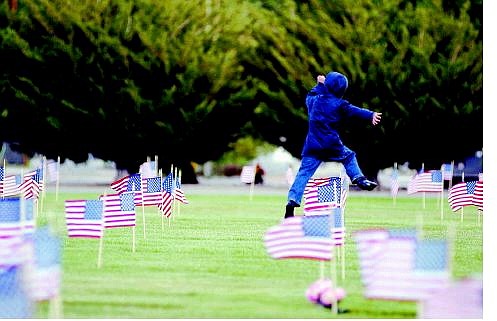 Brad Horn/Nevada Appeal Noah Jennings, 5, of Carson City, jumps over American flags just placed on gravesites of veterans at the Lone Mountain Cemetery in Carson City on Friday.