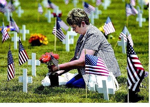 Cathleen Allison/Nevada Appeal Linda Wilson, of Carson City, puts fresh roses on her husband Donald&#039;s grave at the Lone Mountain Cemetery Monday.  Wilson served as an Army medic and was one of many veterans honored during Memorial Day ceremonies around the country.