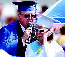 Glen Adair speaks to the graduating class after Charity Ricks and Maria Urbina presented their principal a cap and gown on his last official day of duty during graduation  ceremonies on the football field Saturday.  BRAD HORN Nevada Appeal