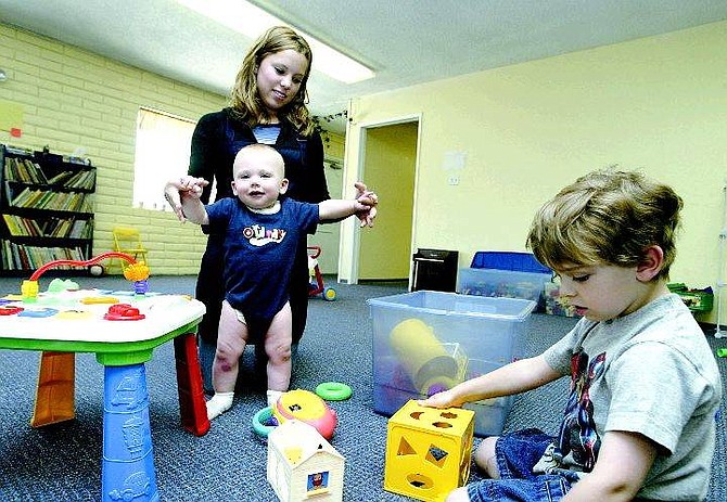 Belinda Grant/Nevada Appeal Shannon Craugh, a caregiver at Kidding Around Preschool and Day Camp, plays with 9-month-old A.J. Kunter and 4-year-old Robert Bush Monday. The camera, top center, sends live video over the Internet to parents.