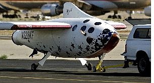 SpaceShipOne, with pilot Michael W. Melvill waving from a porthole, is towed off the runway after a trip to suborbital space at Mojave, Calif., airport Monday.  Associated Press