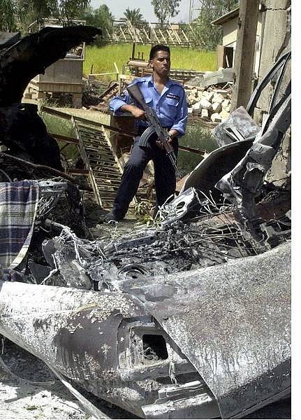 An Iraqi policeman stands at the site of a roadside bomb that went off prematurely, destroying a civilian car and killing it&#039;s occupant in Baghdad, Iraq Thursday, July 8, 2004.(AP Photo/Karim Kadim)